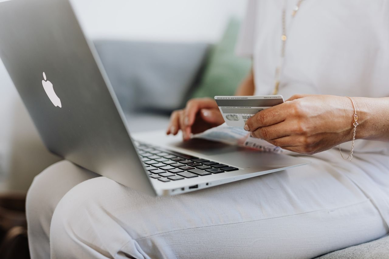 Home Close-up of a person holding a credit card while shopping online using a laptop at home.